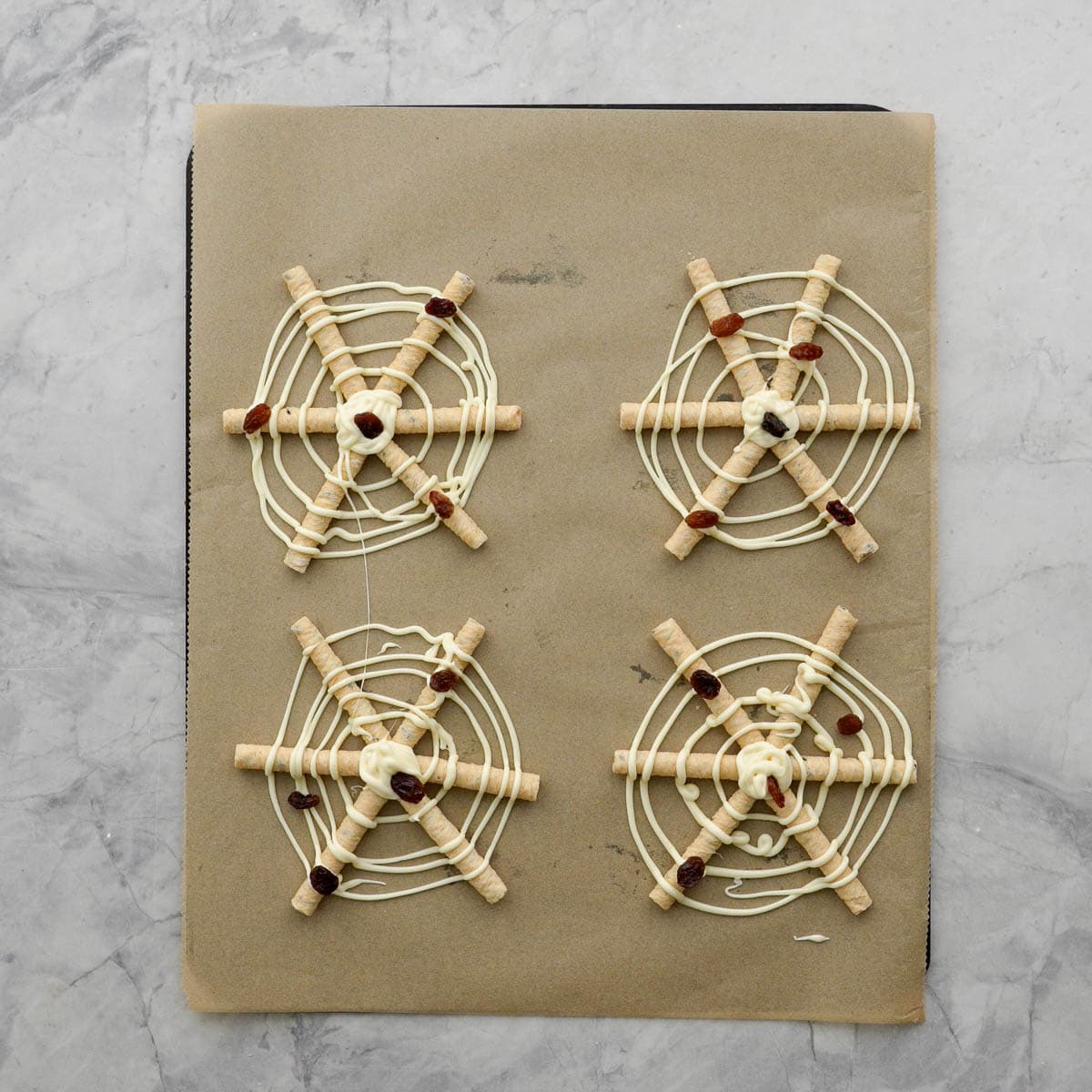 Four Spider Web Pretzels on a lined baking tray.