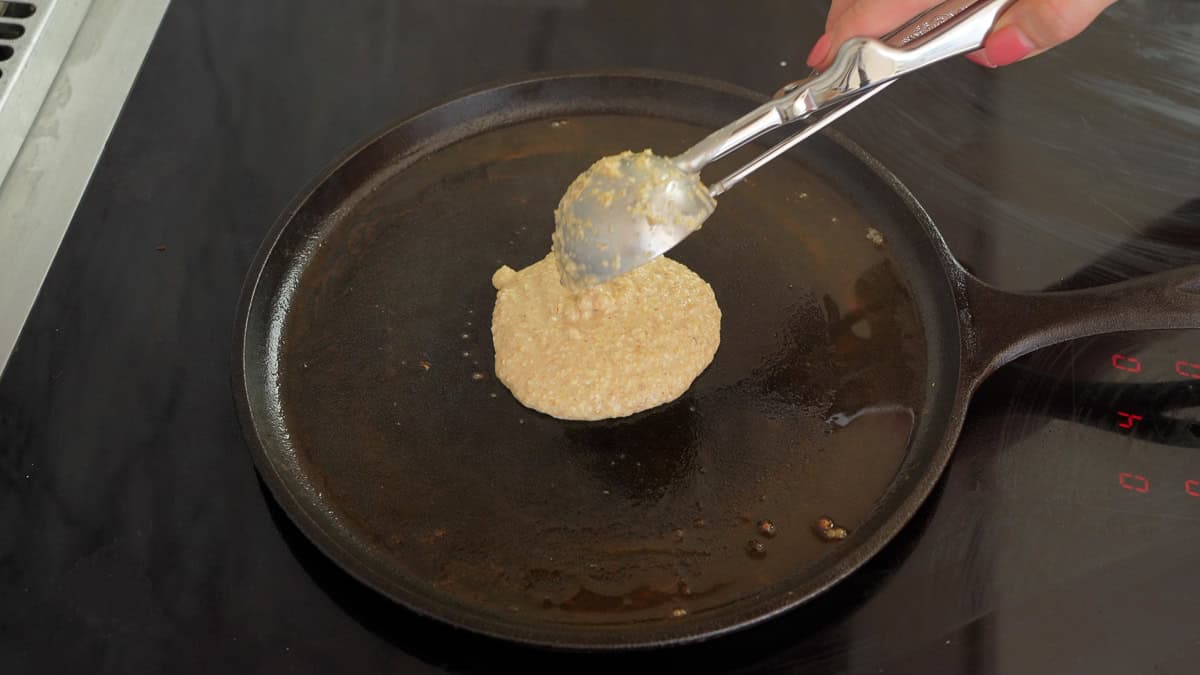 Oat flour pancake mixture being scooped onto a hot flat pan.