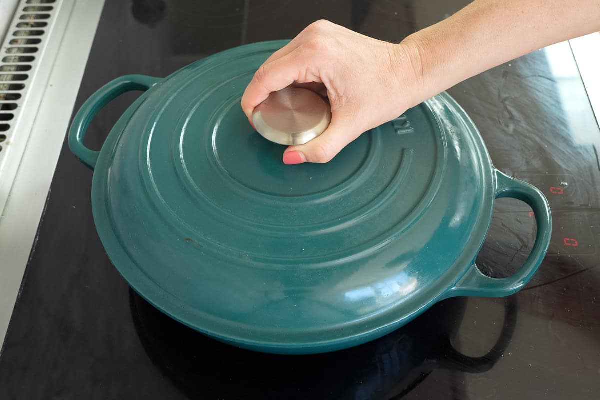 Lid being placed on pan with sausage pasta inside.