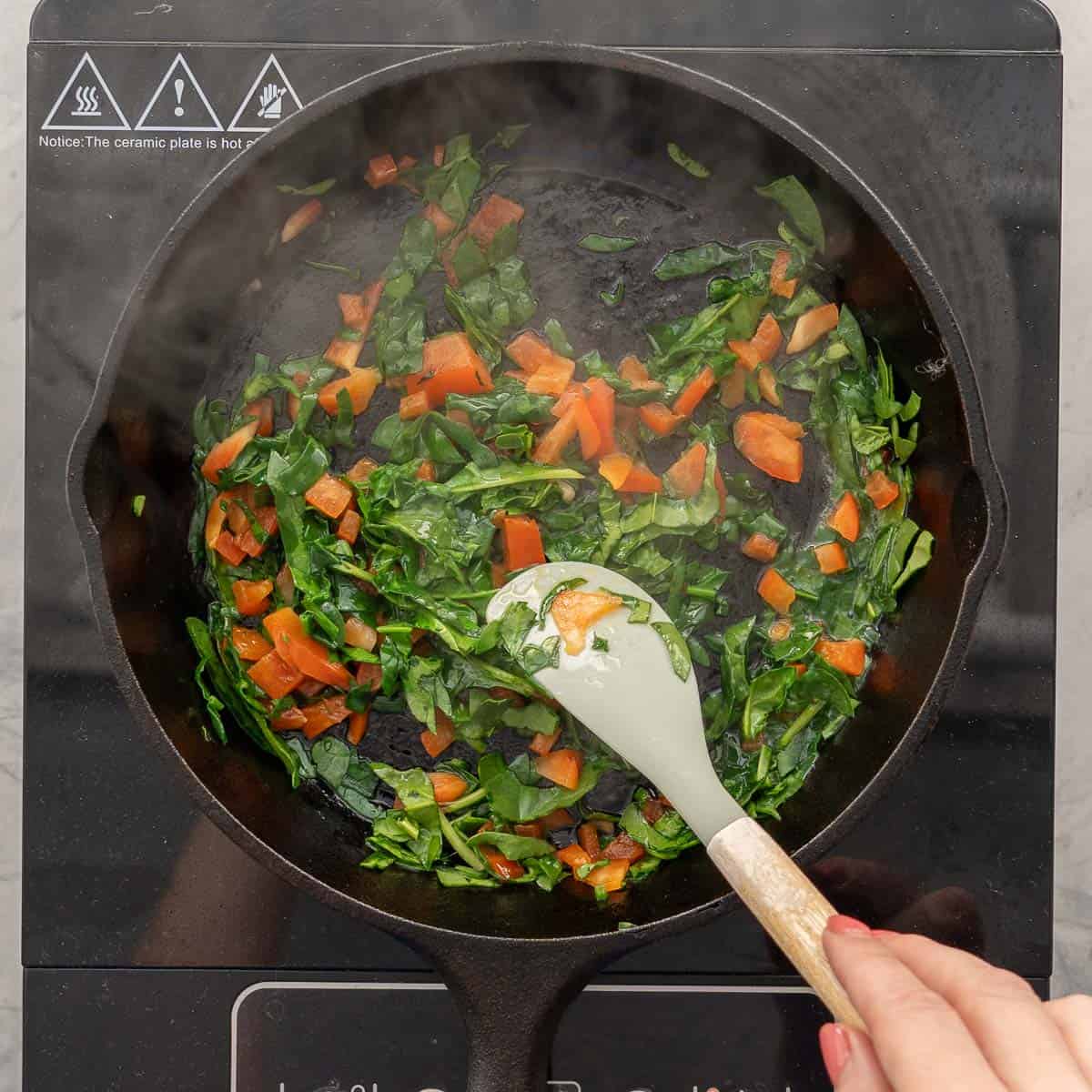 Spinach and Capsicum in pan on stove top sautéing.