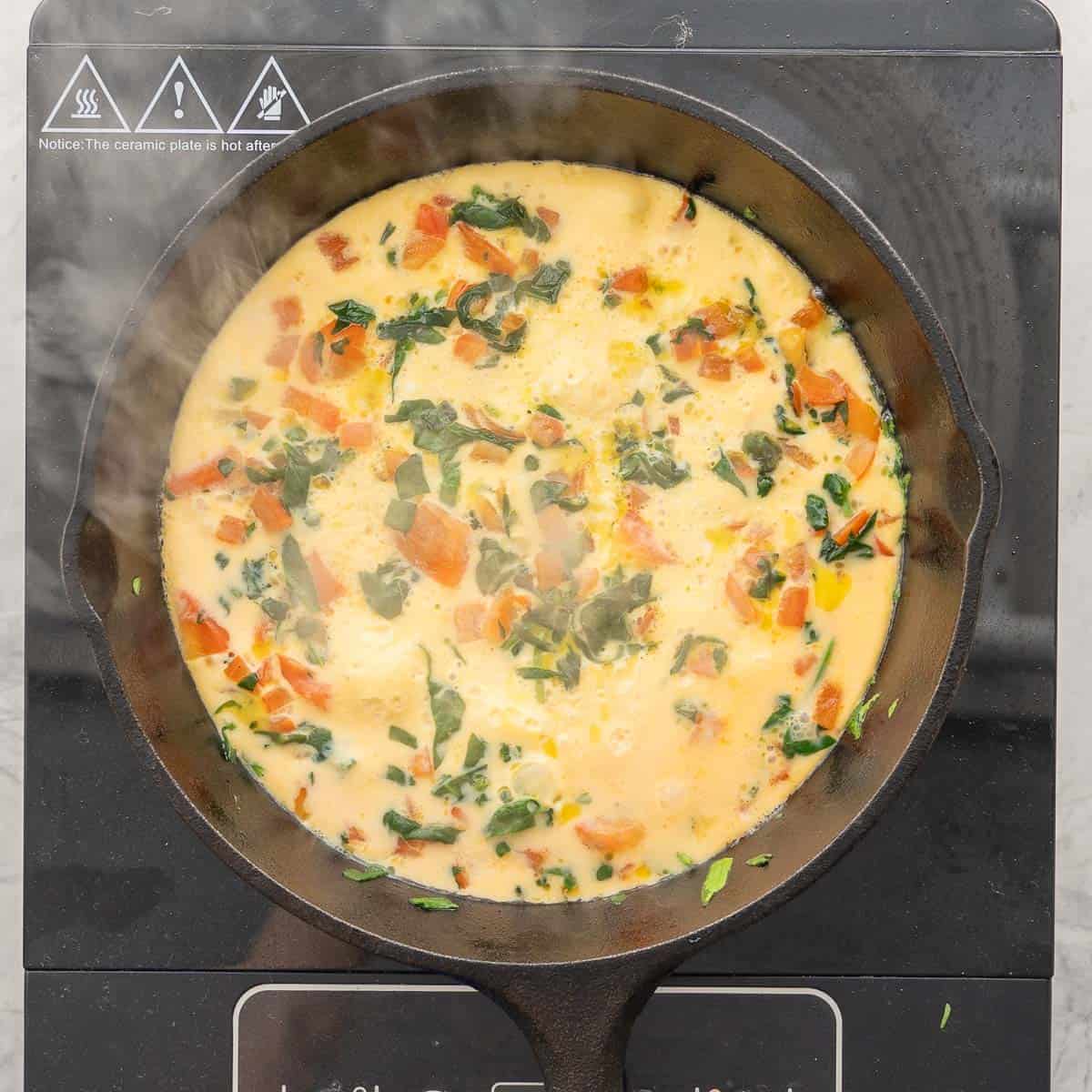 Spinach omelette cooking on stove top.