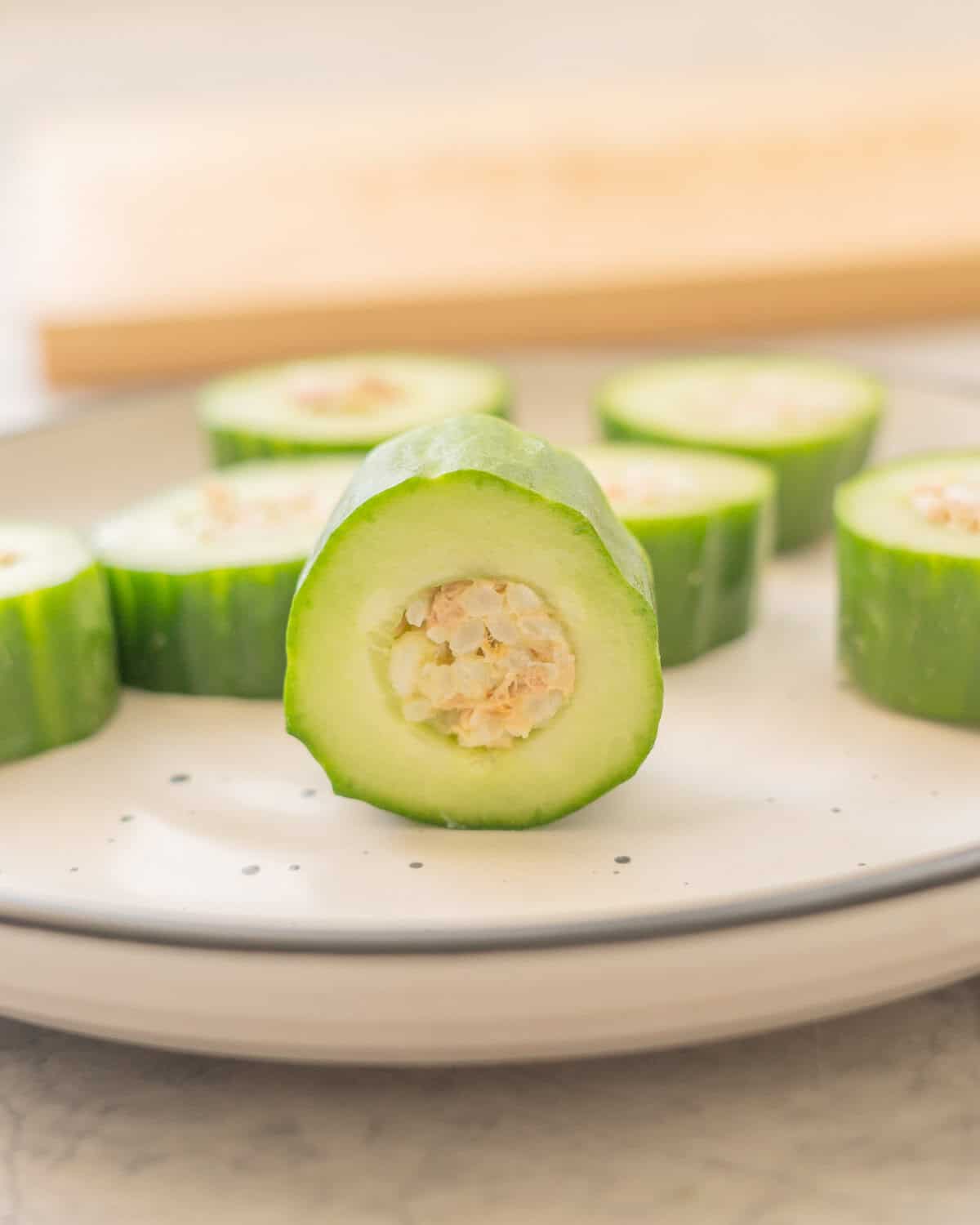 Tuna and Rice mixture stuffed inside hollowed out cucumber pieces on a plate.