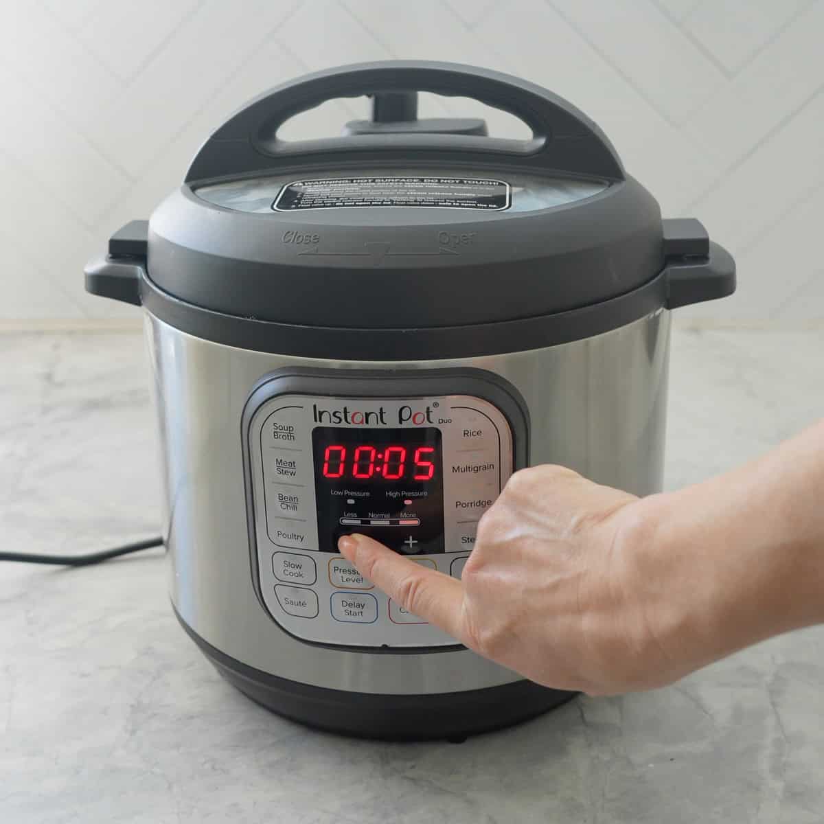 Hand turning on an instant pot.