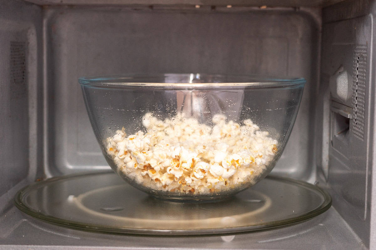 Popped popcorn in glass bowl in microwave.