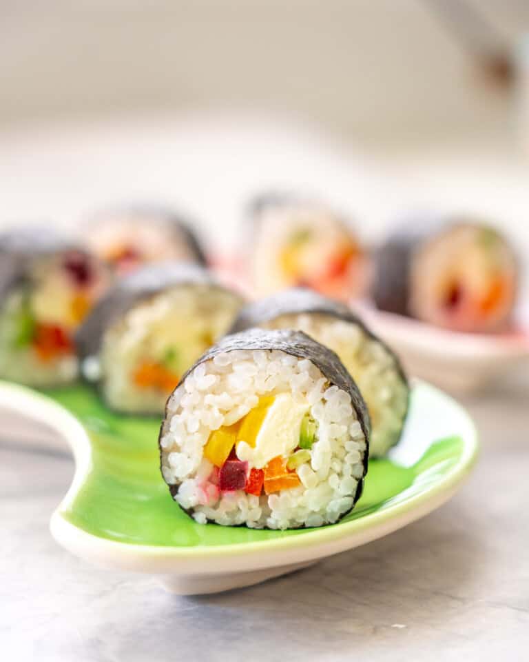 Piece of Rainbow Sushi on a plate showing ingredients inside.