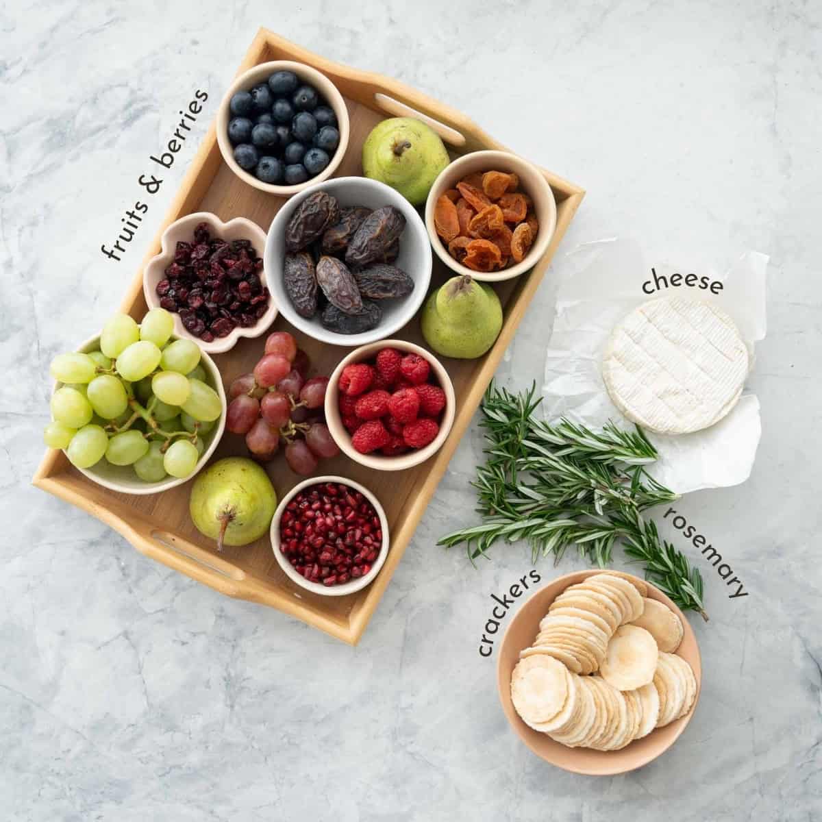 Ingredients for Christmas Cheese Board on benchtop with text overlay.