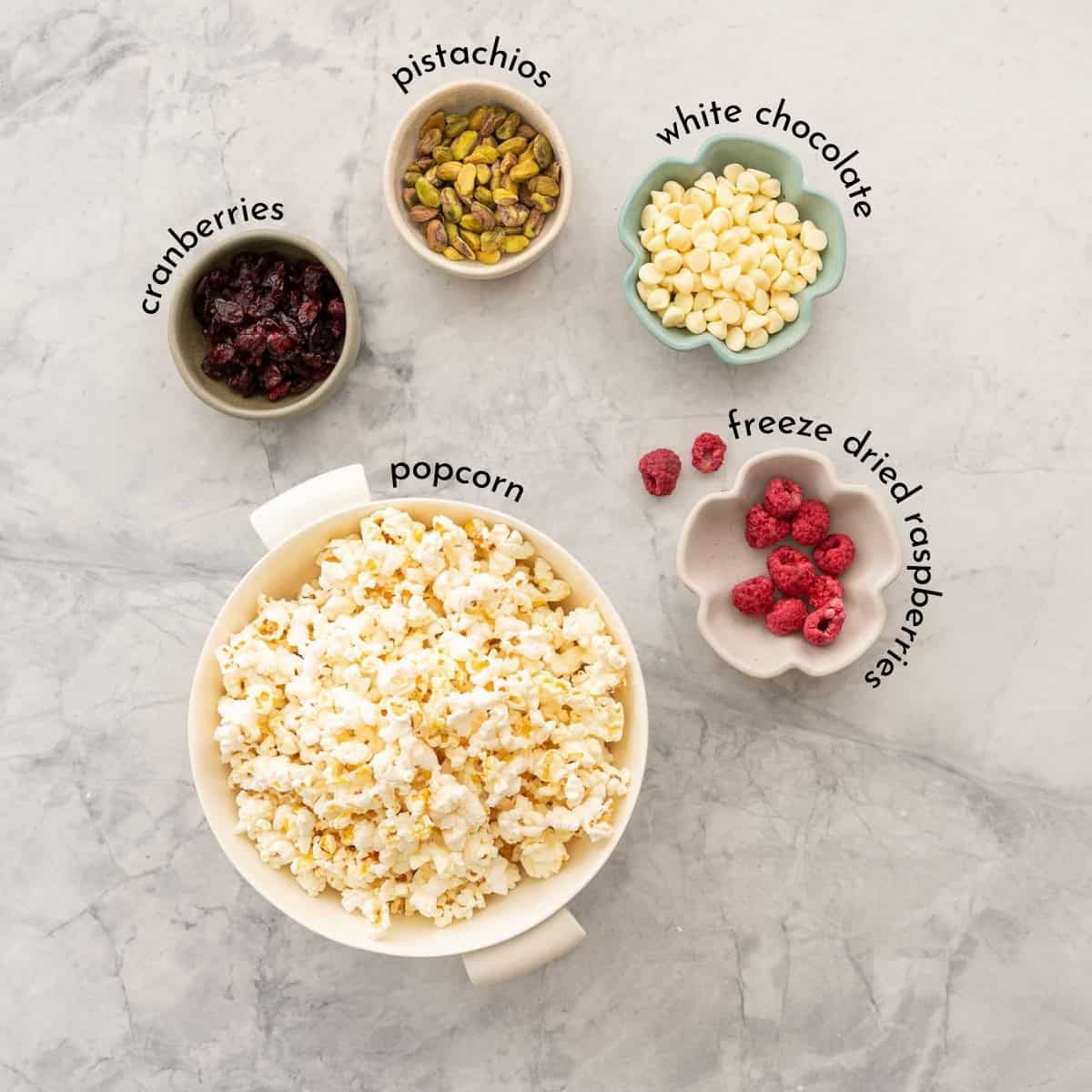 Ingredients for Christmas Popcorn with text overlay on a bench top.