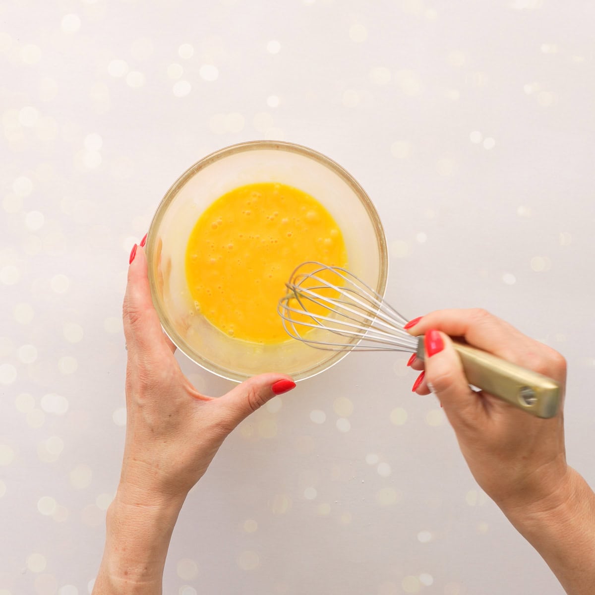 Small bowl on bench top with egg yolk inside being whisked.