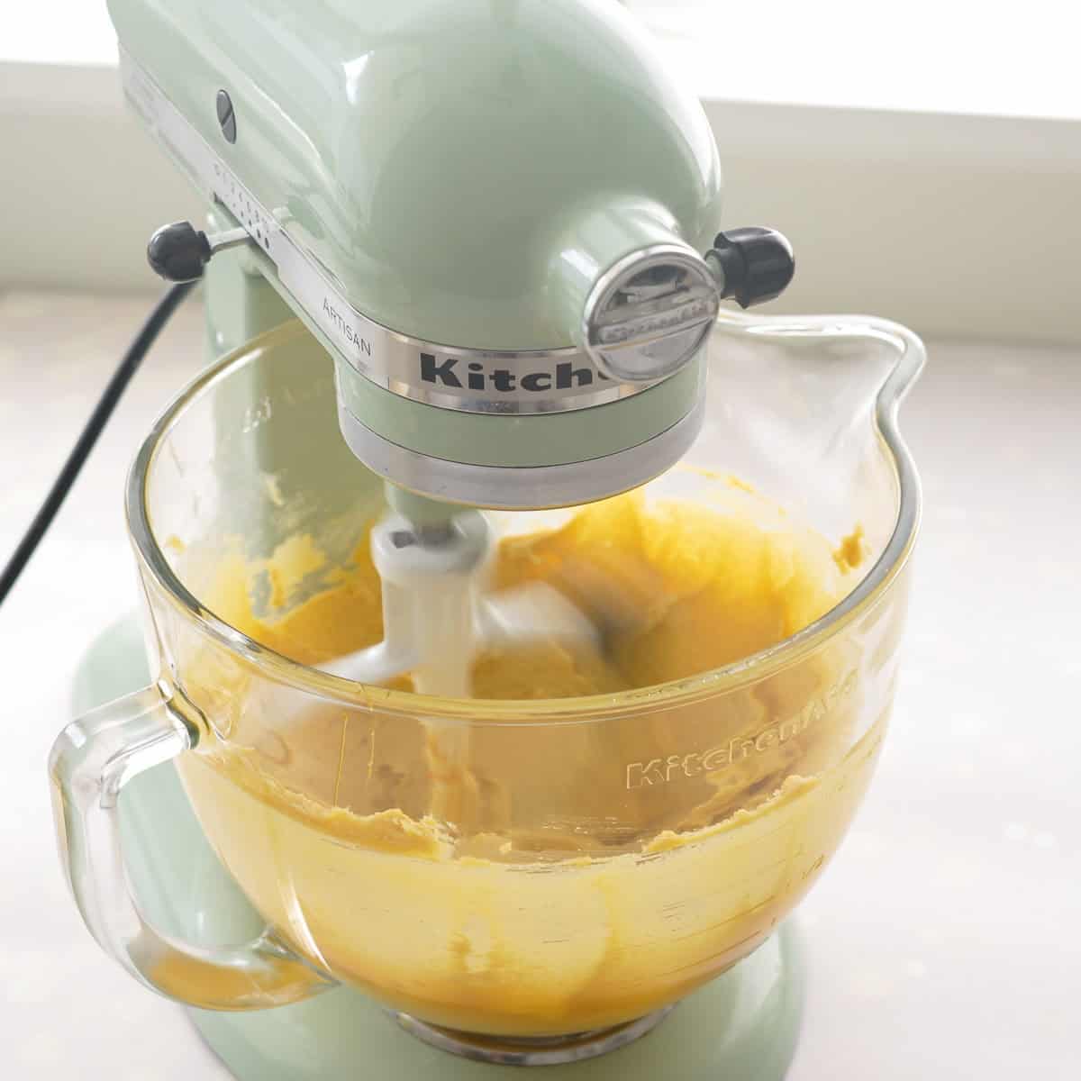 Electric beater on bench top with the butter, caster sugar and golden syrup being beaten.