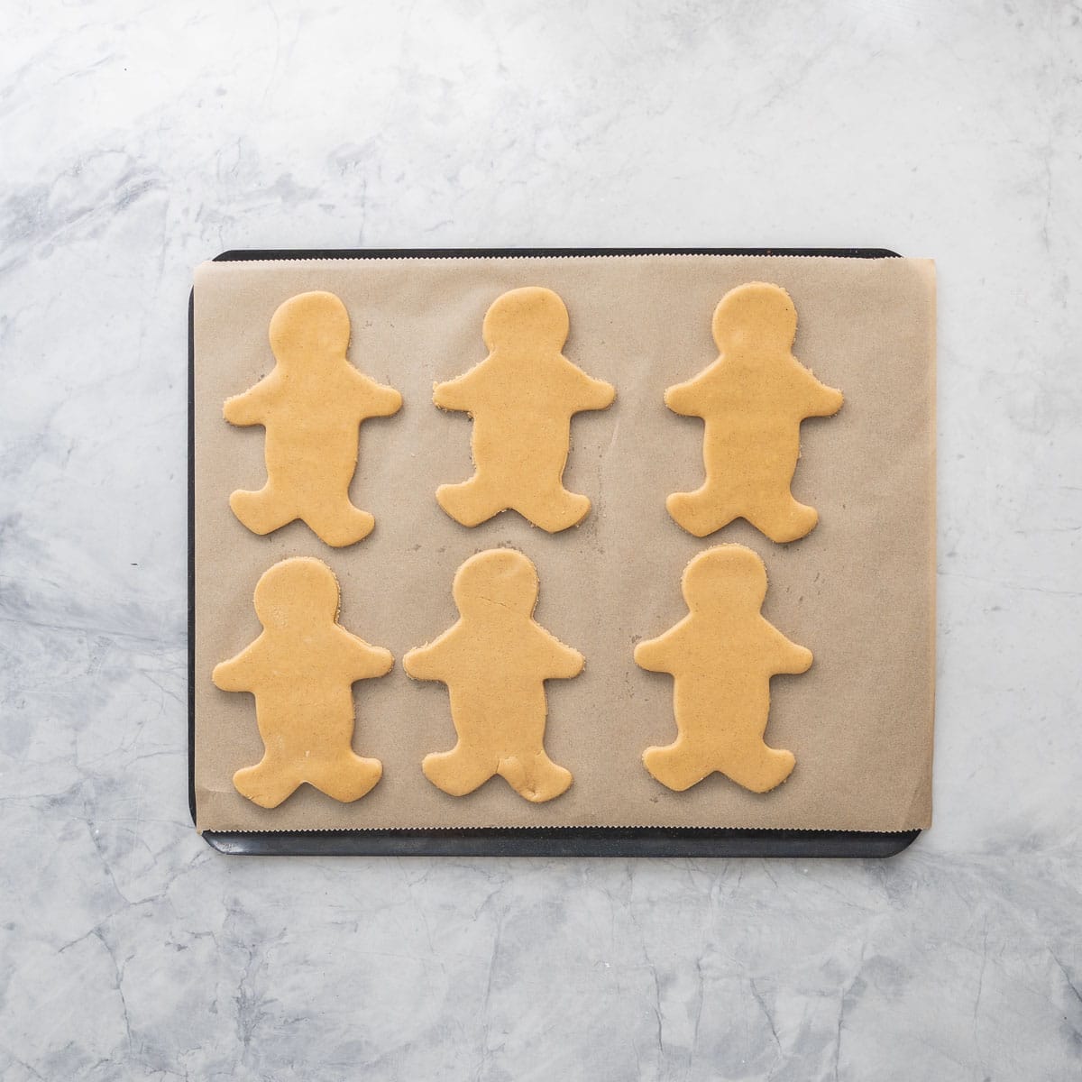 Six GF Gingerbread cut outs on baking tray lined with baking paper.