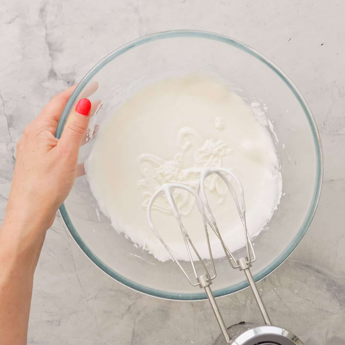 Royal icing whisked together in a big glass bowl on benchtop.