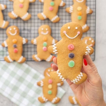 GF Gingerbread held up to the camera decorated with three colourful circle jellys down the centre, royal icing squiggly lines on feet and arms, smiley face.