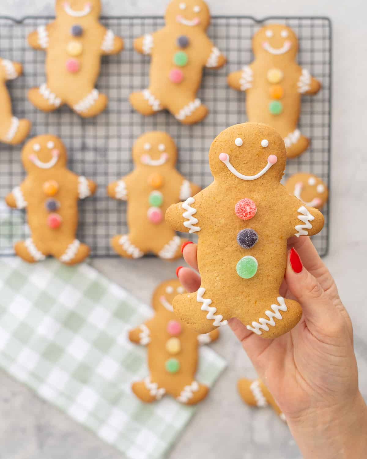 GF Gingerbread held up to the camera decorated with three colourful circle jellys down the centre, royal icing squiggly lines on feet and arms, smiley face.