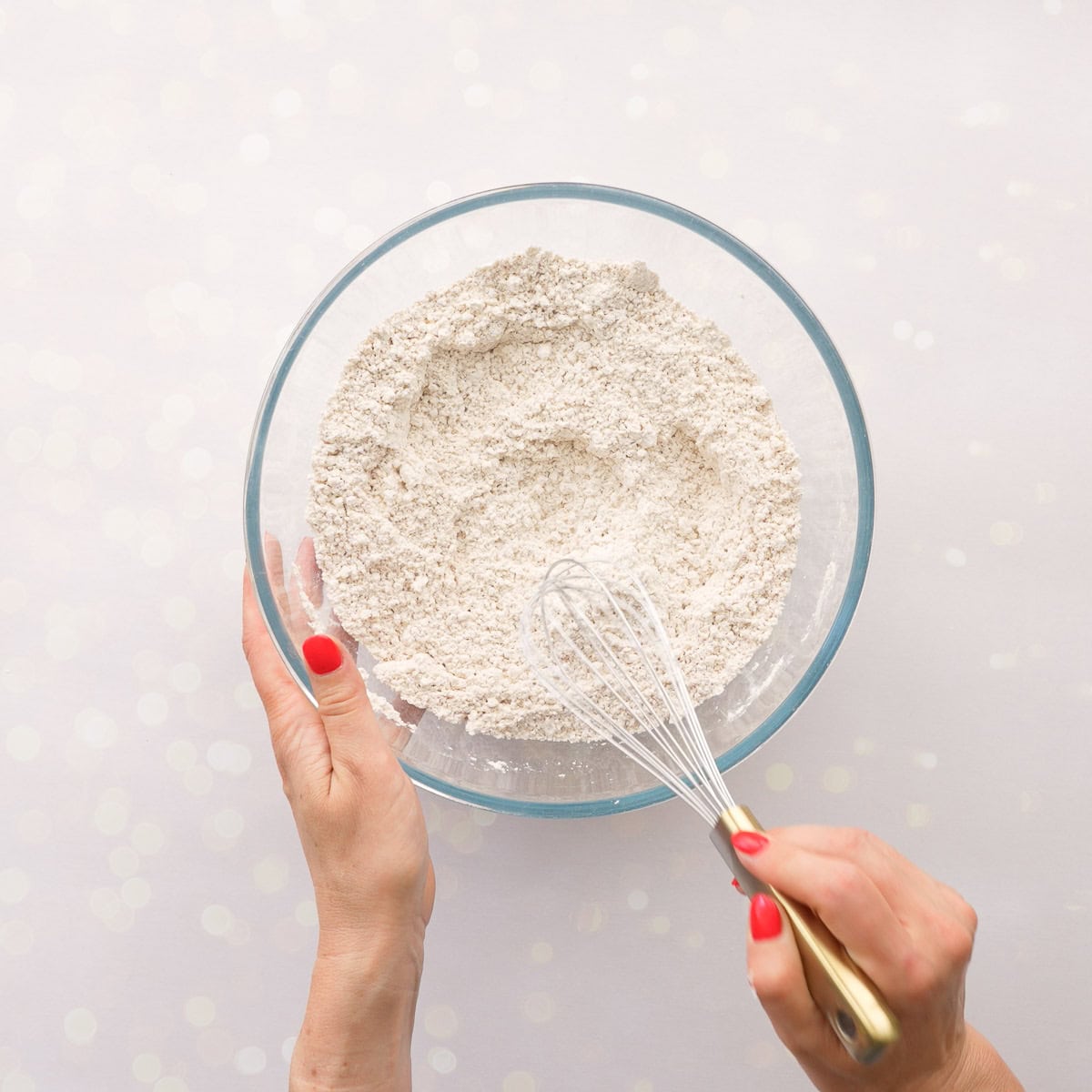 Dry ingredients for Gluten free gingerbread in a glass bowl on bench top being whisked together. Flour, baking soda, ginger, cinnamon and nutmeg