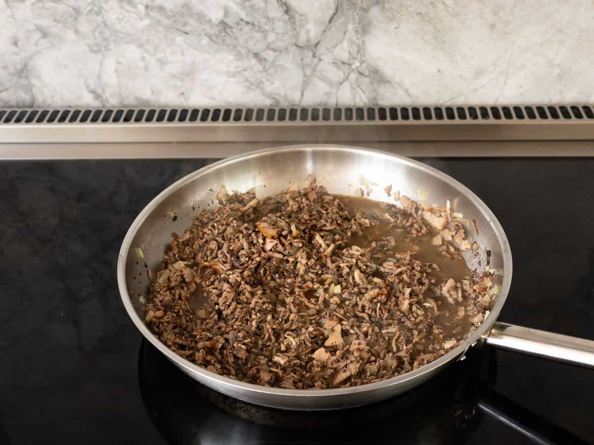 Ground mince, grated mushrooms, sautéed onion, garlic and bacon in frying pan.