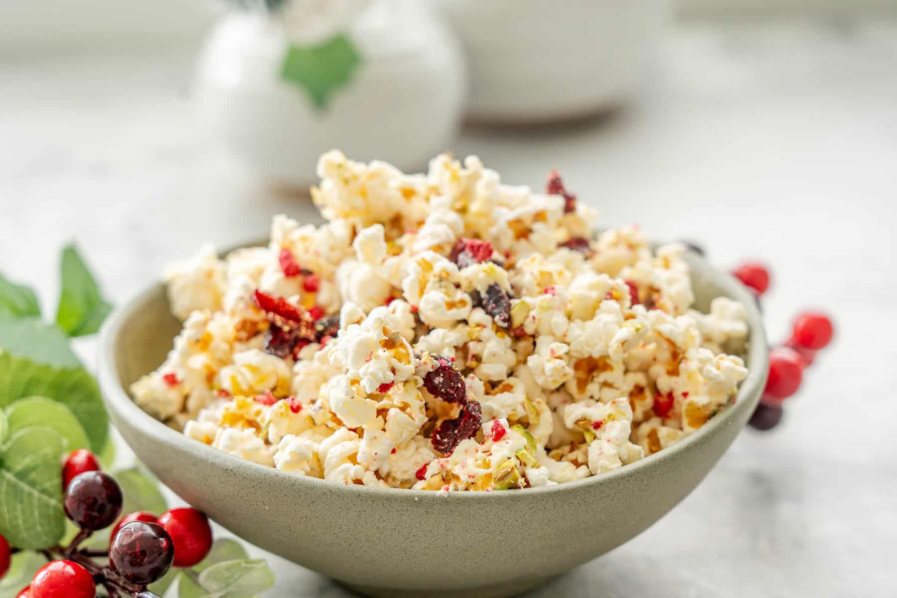 Christmas Popcorn in a ceramic bowl on bench top with Christmas decorations around.