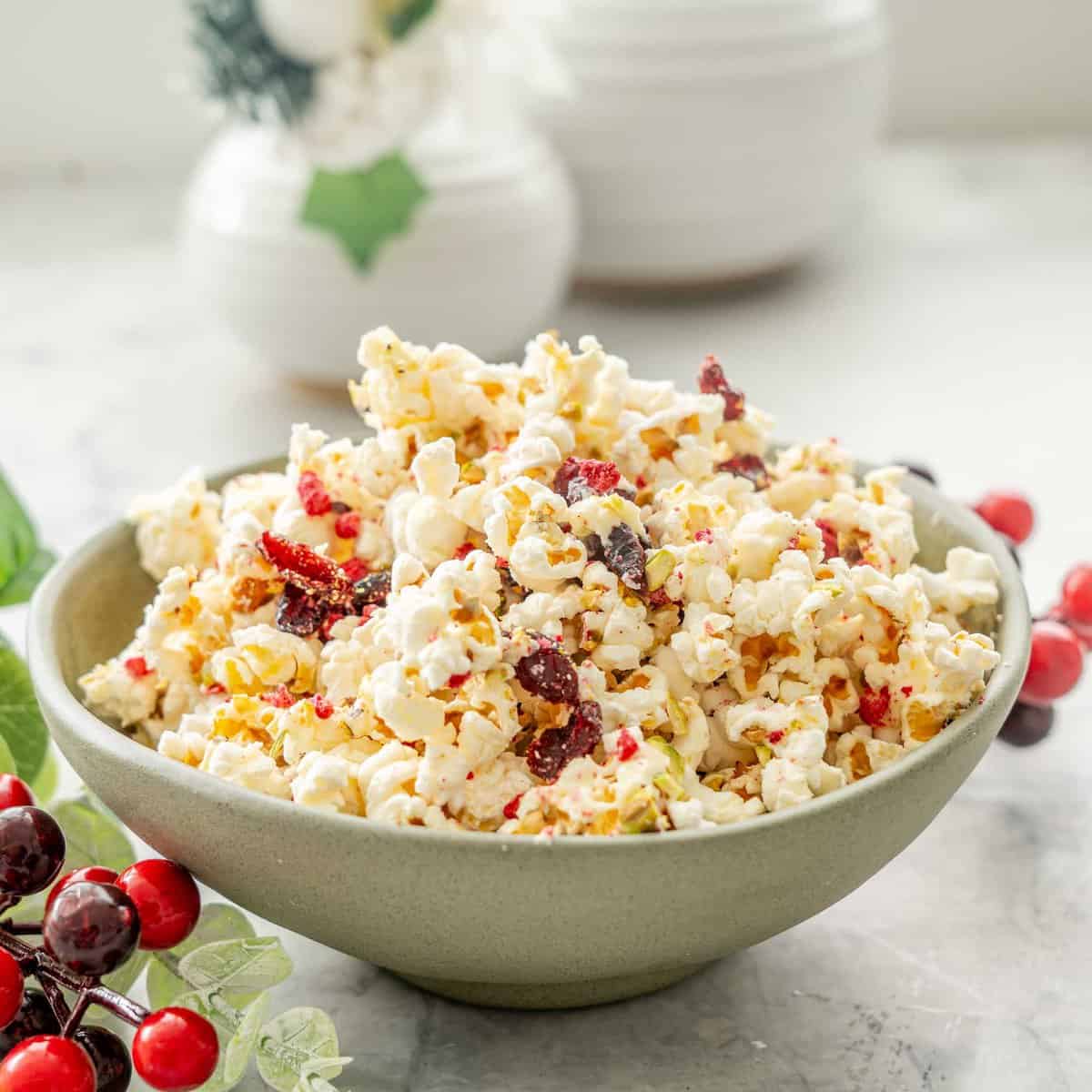 Christmas Popcorn in a ceramic bowl on bench top with Christmas decorations around.