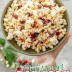 Hand holding Christmas Popcorn in a ceramic bowl above bench top with Christmas decorations around. With text overlay: Christmas popcorn, easy holiday treat.