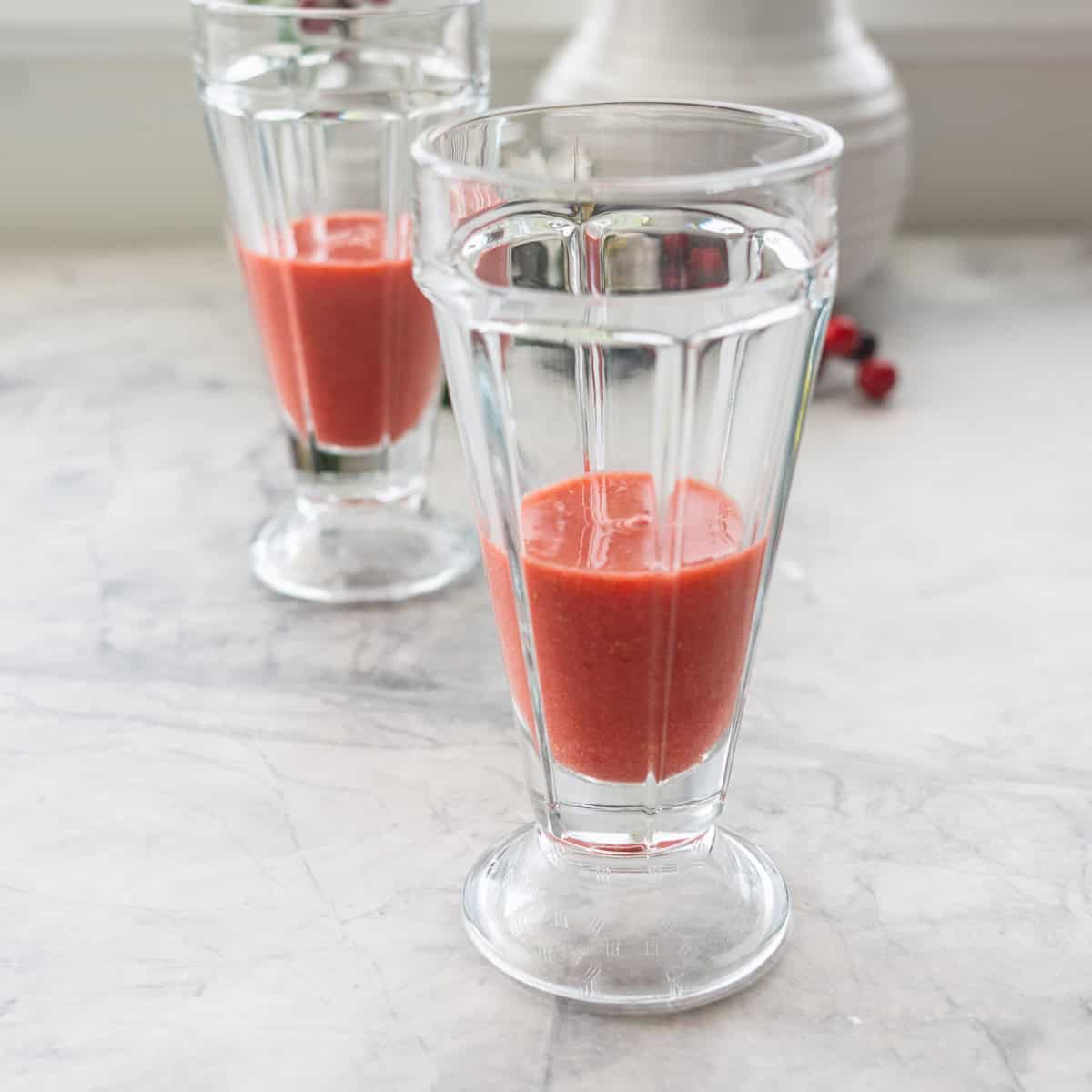 Red Christmas smoothie filling quarter of a tall glass.