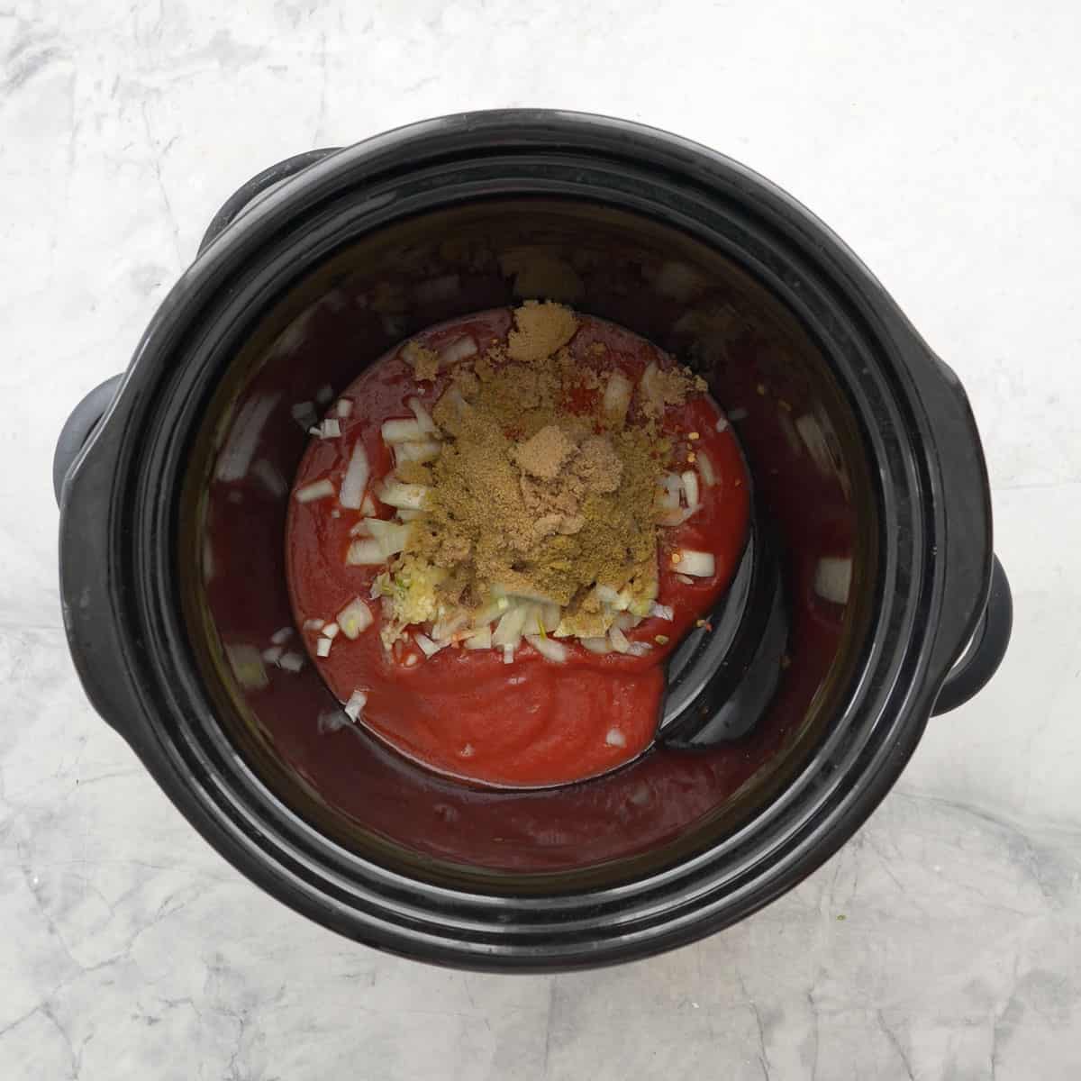 Diced onion, crushed garlic, tomato puree, spices, brown sugar and cocoa powder into the bowl of crockpot.