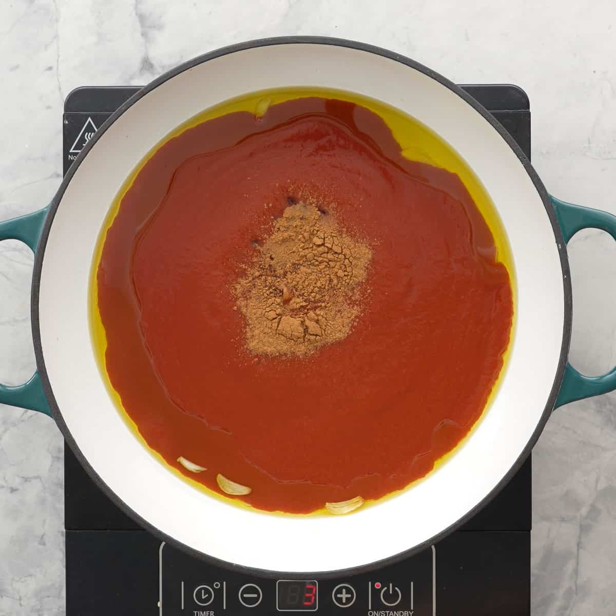 Tomato puree, cinnamon and maple syrup added into oil and garlic on stove top.