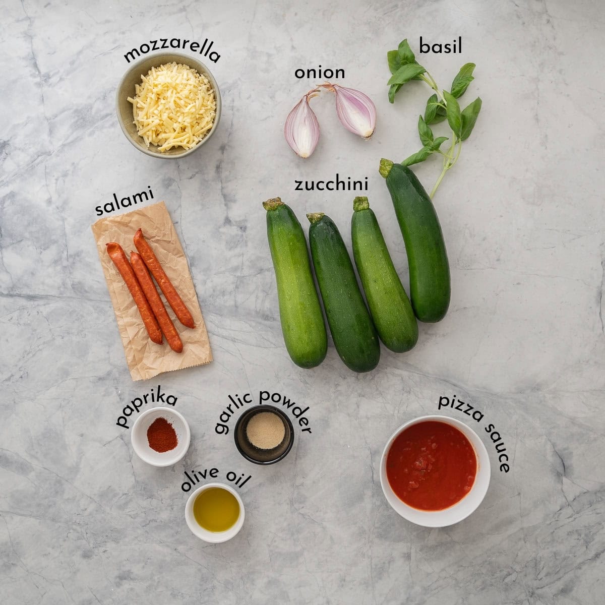 Ingredients for Zucchini Pizza Boats on benchtop with text overlay.