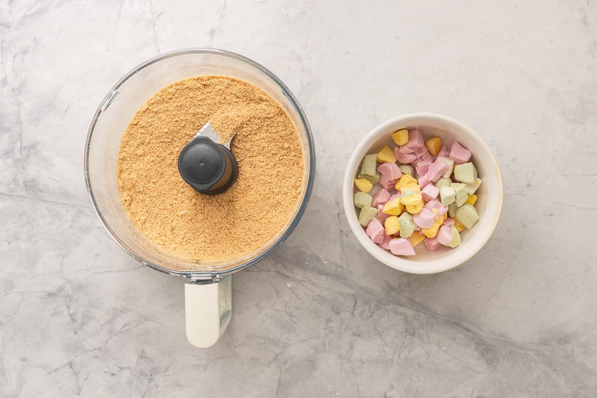 Biscuits crushed in a food processor and Explorer lollies chopped into small pieces in a bowl on bench top. 