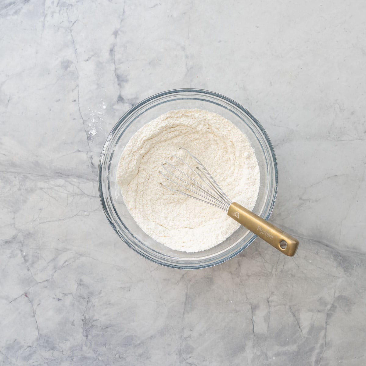 Dry ingredients; flour, baking powder, cinnamon, sugar and salt in a bowl with whisk inside on bench top.