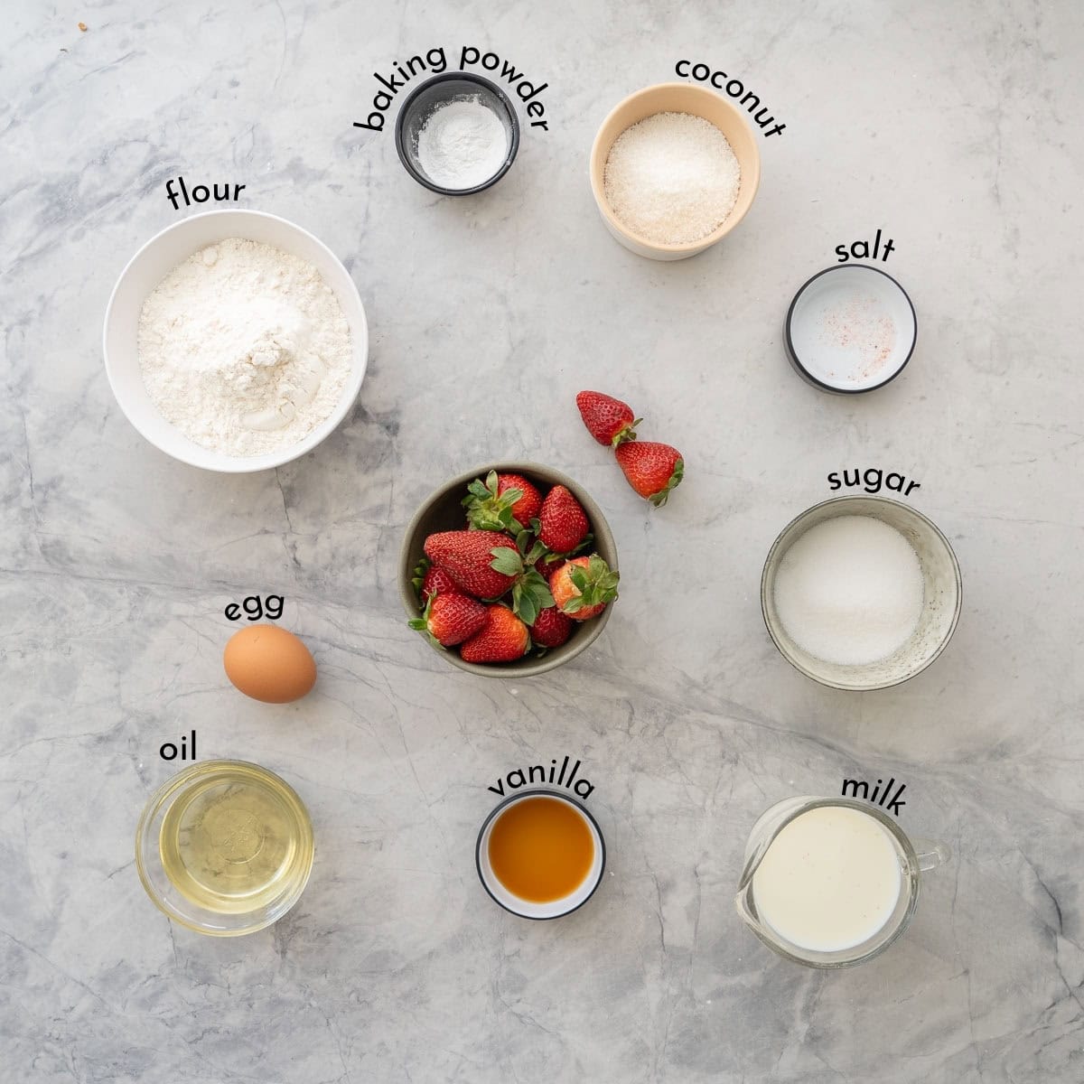 Ingredients for strawberry muffins with text overlay on benchtop.