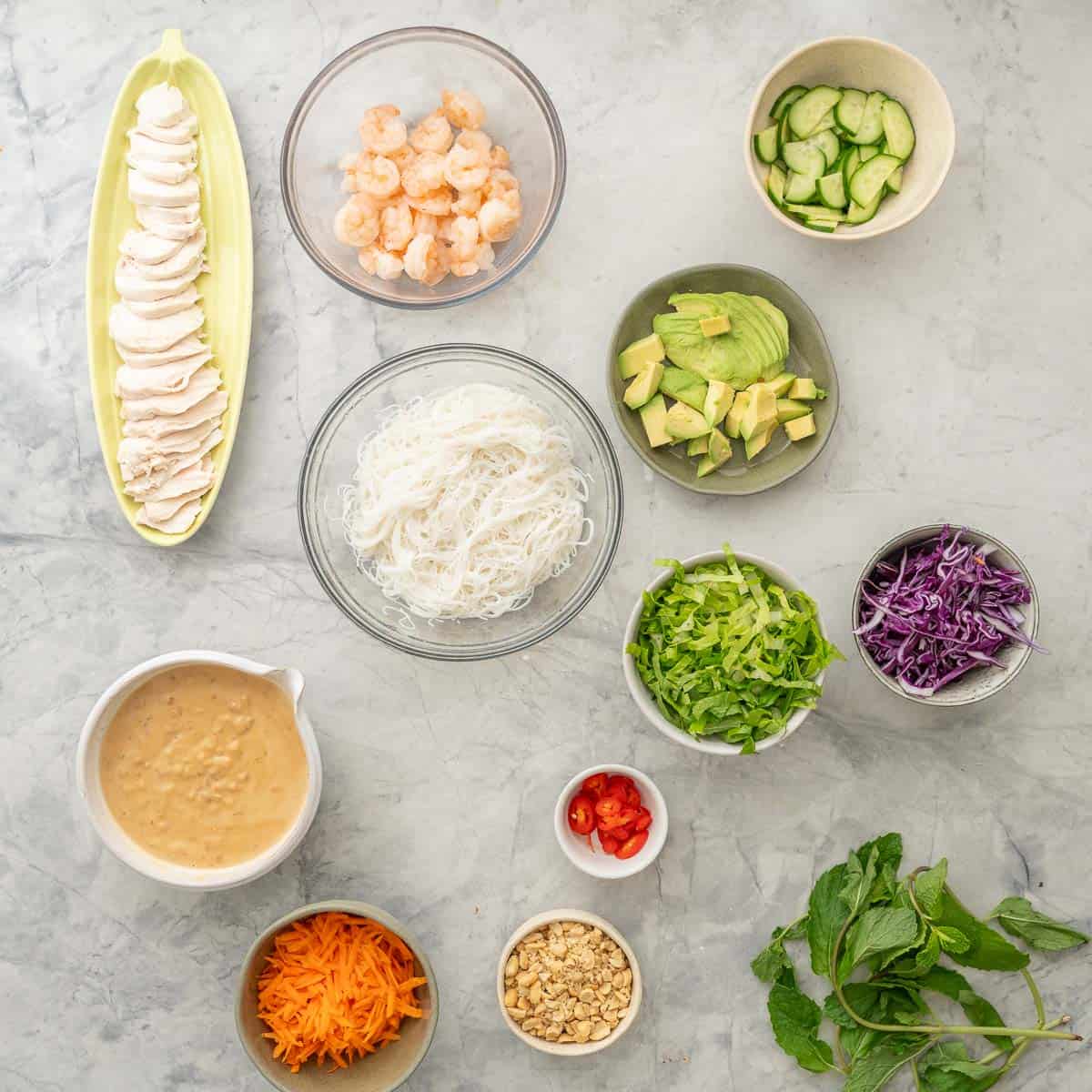 Topping ingredients for summer roll bowls on bench top.