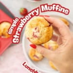 A muffin studded with red strawberry pieces being held above a plate. Text overlay: simple strawberry muffins, lunchbox recipe.