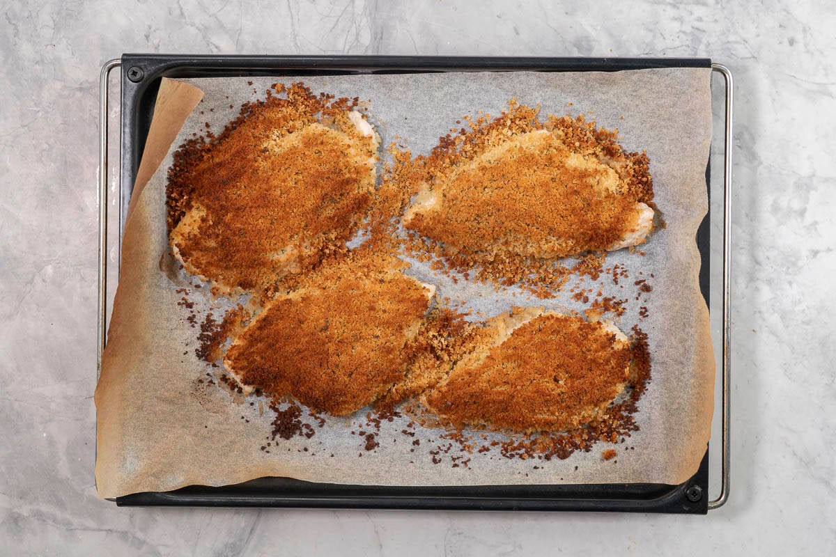Four cooked chicken breasts with crispy coating on top.