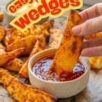 Crispy seasoned potato wedges on lined baking tray with two ramekins, aioli and sweet chilli sauce, hand holding a wedge dipping into sweet chilli sauce. Twxt overlay says: easy baked wedges. kids love this side dish.