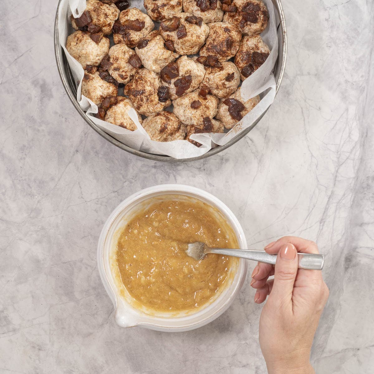 Fork mixing together almond/peanut butter, maple syrup, applesauce, and salt.