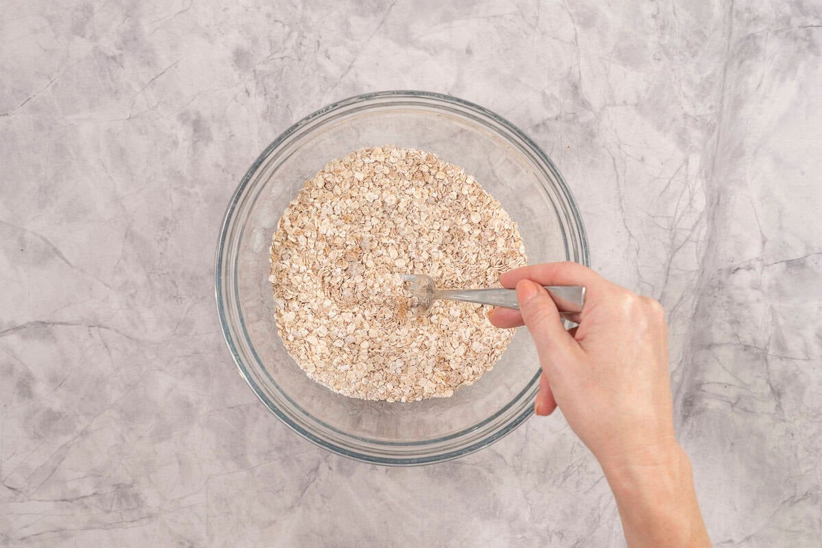 Hand holding a fork mixing together dry ingredients.