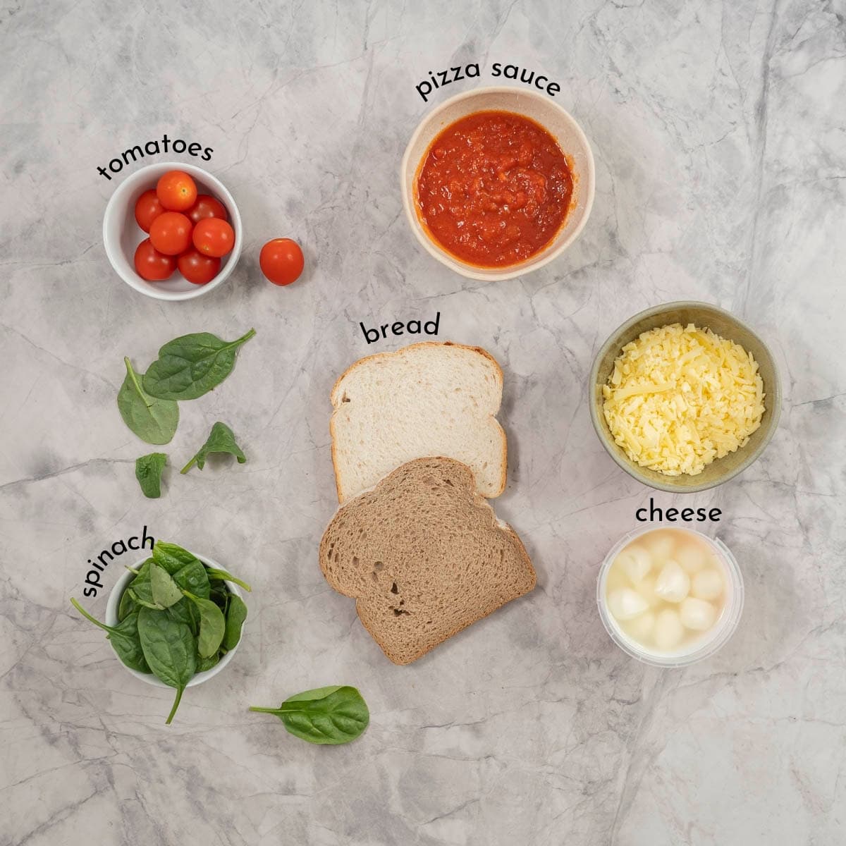 The ingredients to make pizza on a piece of toast laid out on a bench top. 
