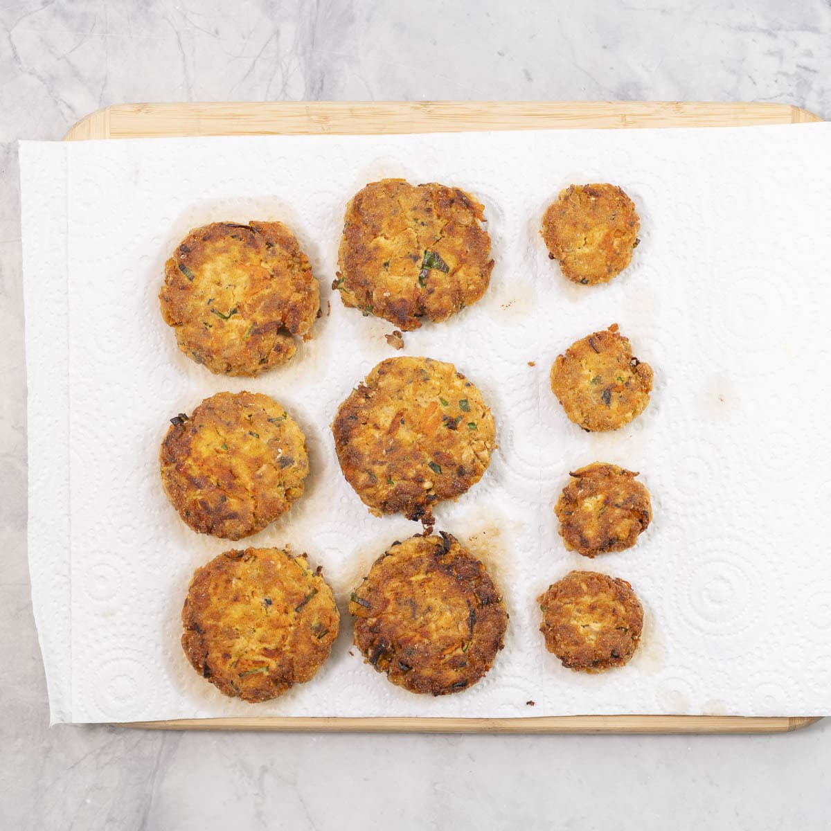 Crispy salmon patties on a paper towel on chopping board.