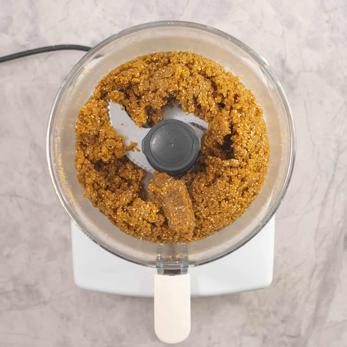 Ingredients for apricot bars inside food processor mixed together.
