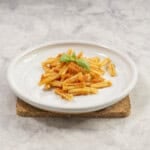 A plate of pasta with tomato sauce and basil leaves.