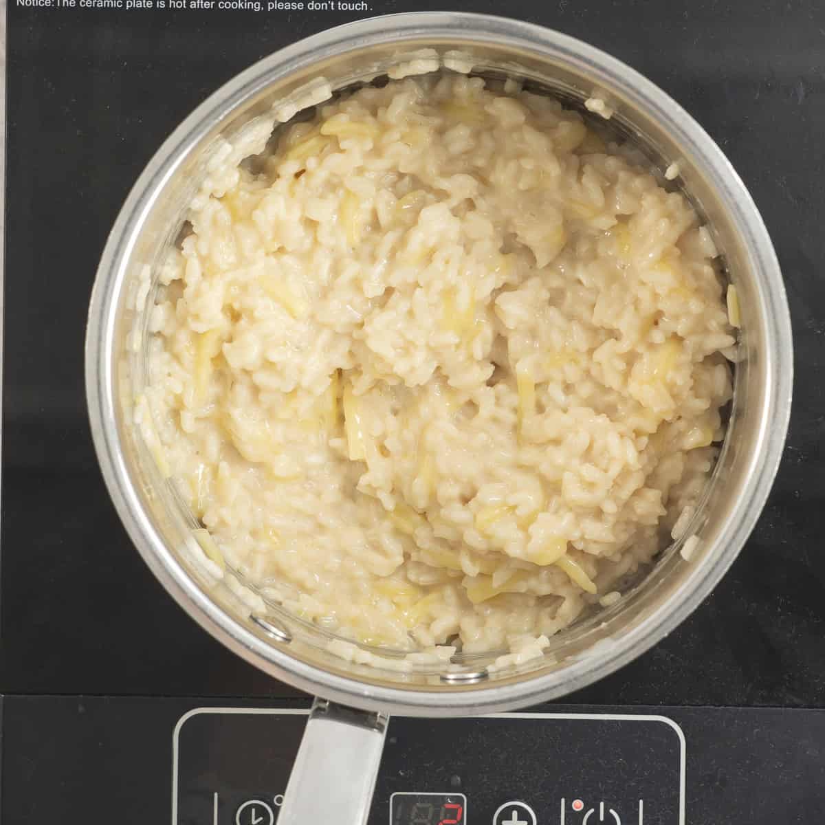 Pot on electric element with rice and cheese cooking inside.