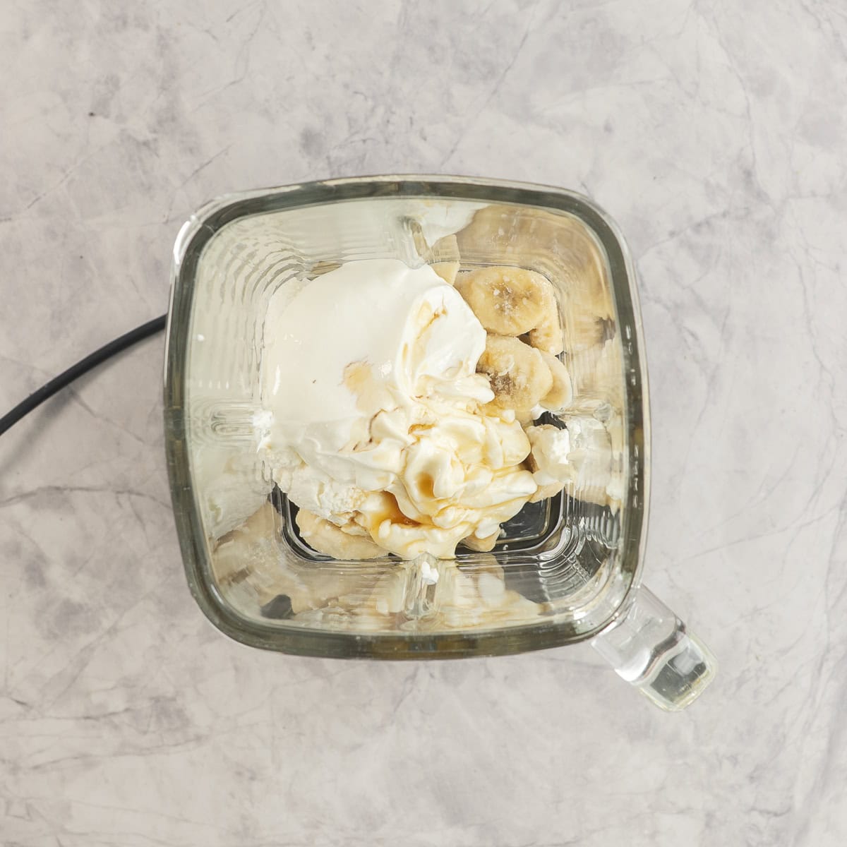 Ingredients for healthy banana pudding in blender on benchtop.