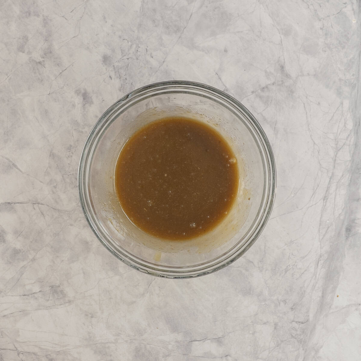 Wet ingredients, brown sugar, egg, vanilla, melted butter combined in glass bowl on benchtop.