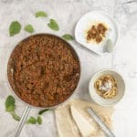 Sauce pan of bolognese on benchtop next to a dinner bowl and a baby plate with serving inside.