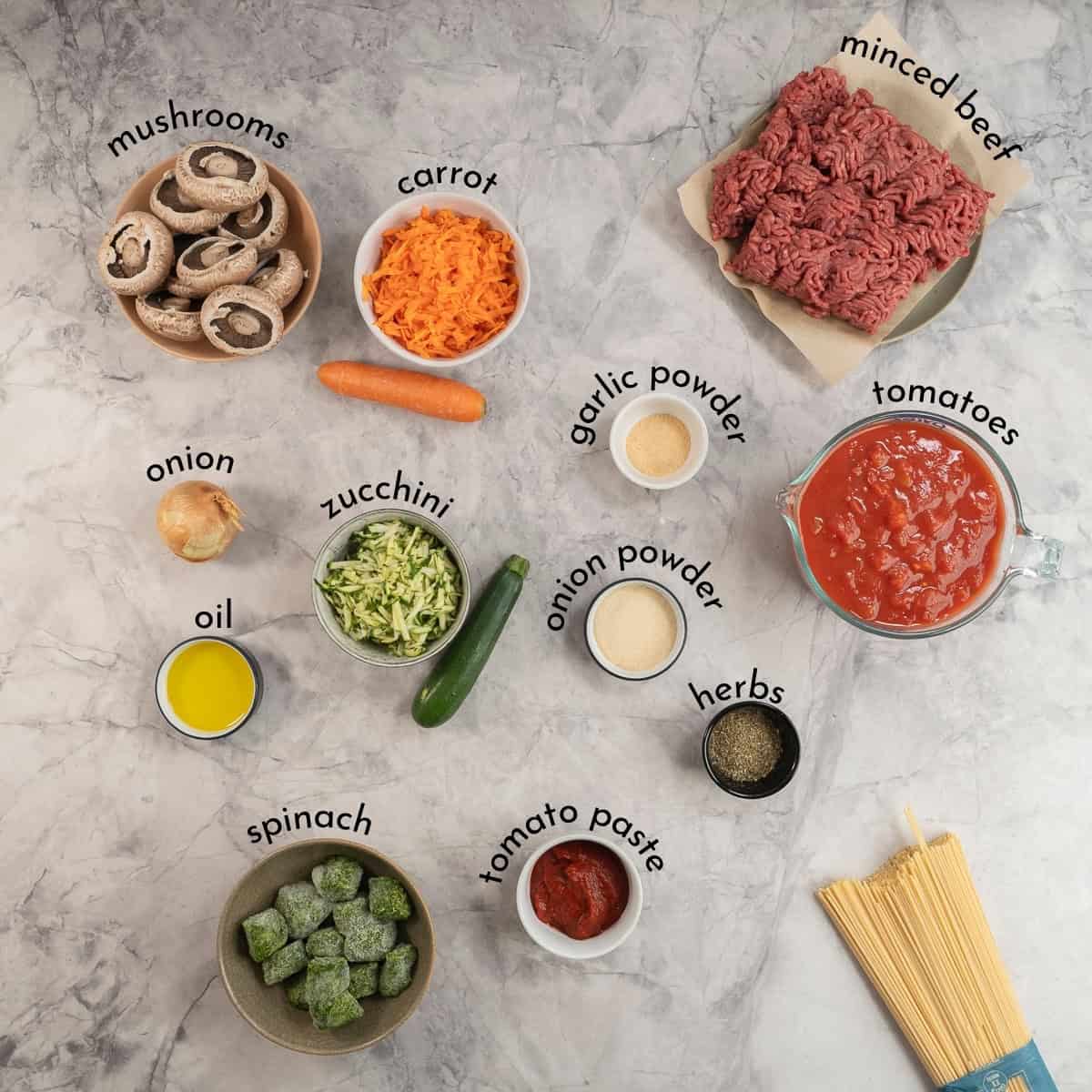 Ingredients for bolognese on marble bench top with text overlay.