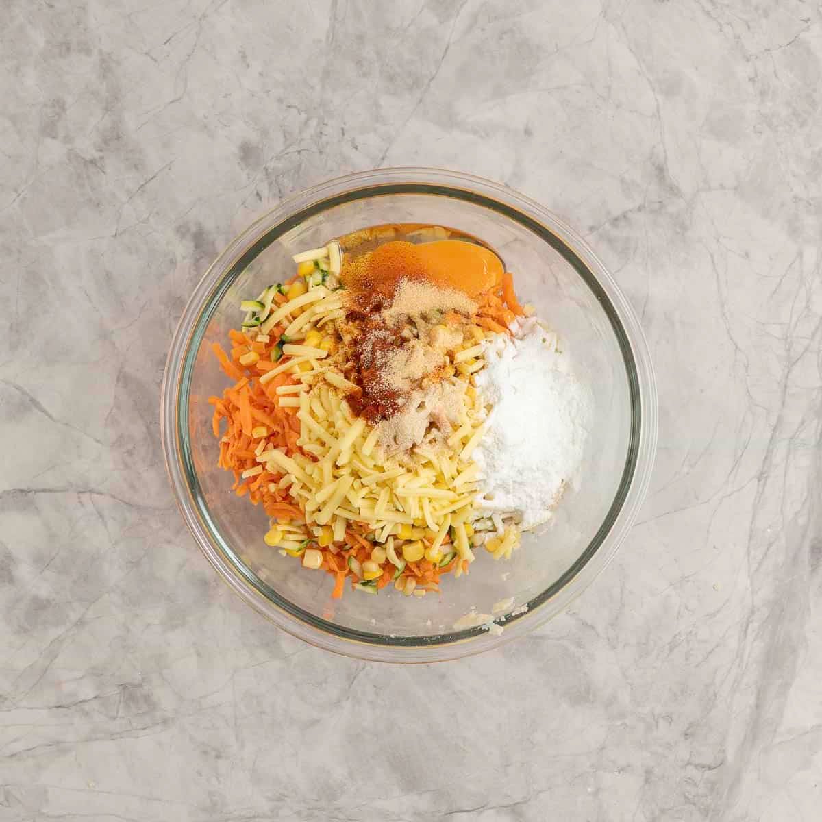 All ingredients inside a large glass bowl on marble bench top for vegetable nuggets.