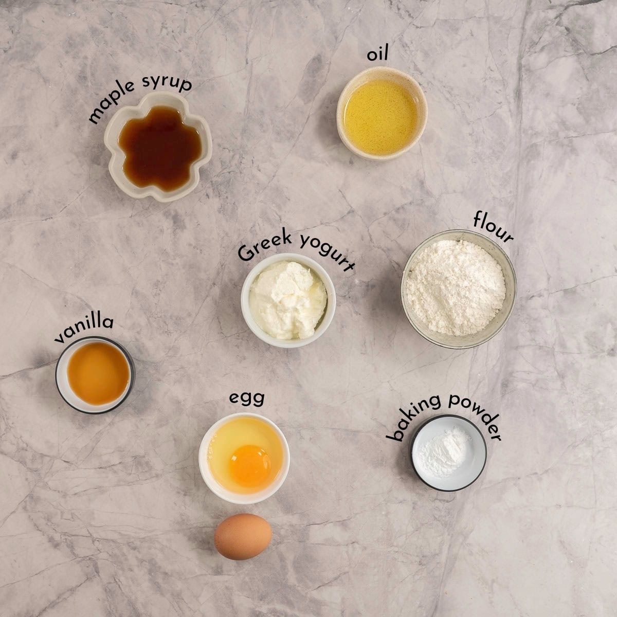 Ingredients for yogurt muffins on marble bench top with text overlay.