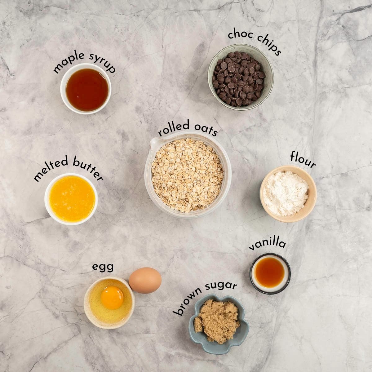 Ingredients for granola bars with text overlay on bench top.