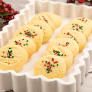 Whipped shortbread on a white tray with Christmas decorations.