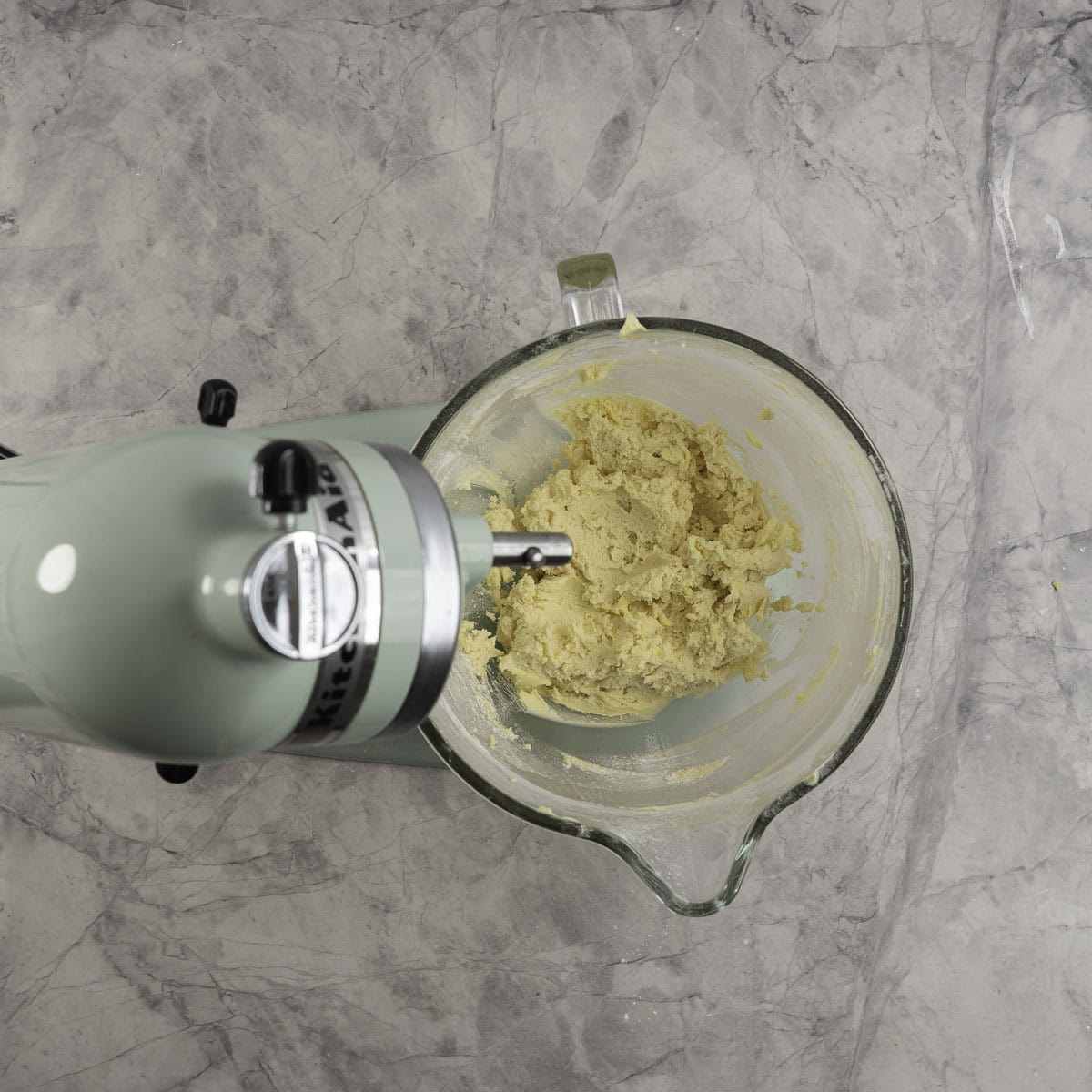 Shortbread dough in the glass bowl of a stand mixer. 