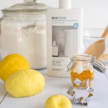 Yellow playdough on a marble bench infront of flou, turmeric and dishwashing liquid.